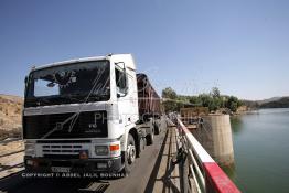 Image du Maroc Professionnelle de  Un poids lourd traverse le pont du Barrage Machraa Hamadi dont la capacité est de 42 Millions de m3, est construit sur l'Oued Moulouya, il permet, depuis 1956, d'approvisionner la région et d'irriguer les terres de cultures, ce barrage fournit en eau potable les ville de Nador, Oujda, il permet également l'approvisionnement des centre de Taourirte et El Aïoun Sidi Mellouk. Samedi 1er octobre 2005. (Photo / Abdeljalil Bounhar) 